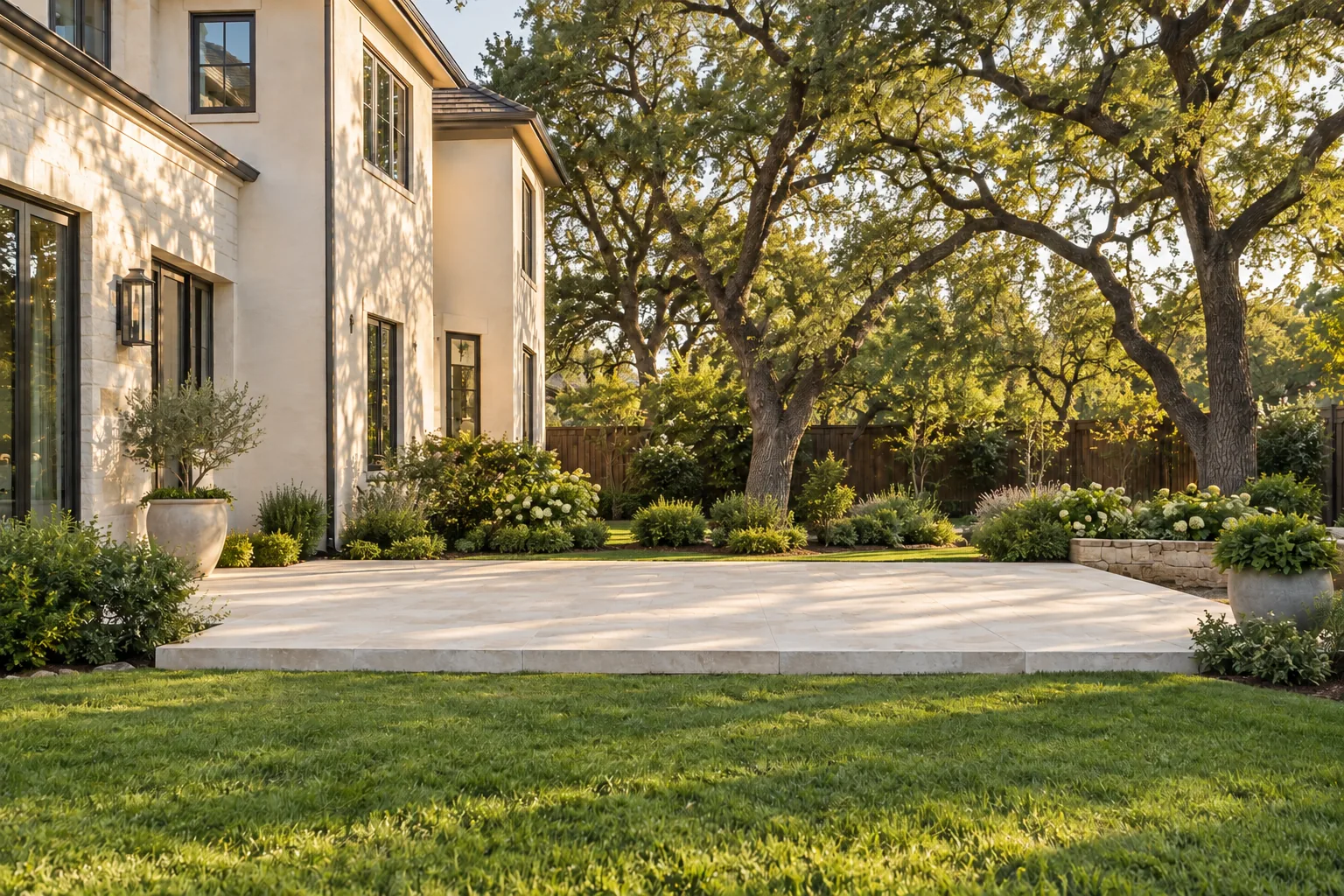 Design visualization of an uncovered stone patio beside a home and mature oak trees